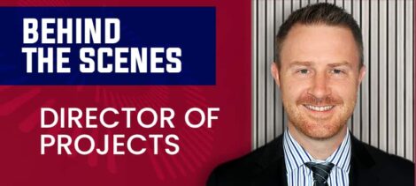 Smiling man in a suit in front of a red background with text reading 'Behind the Scenes, Director of Projects'.