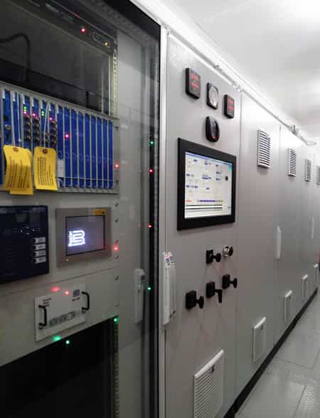 Industrial control panel with digital displays and control switches in a modern facility.