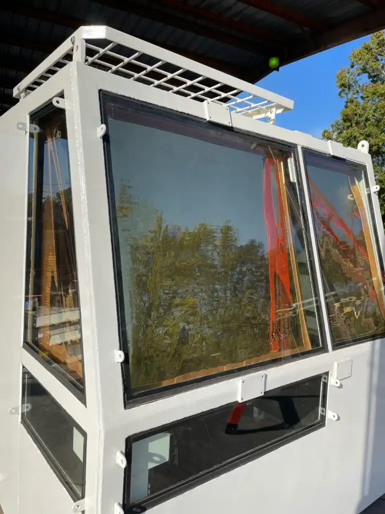 Modular white structure with large tinted windows reflecting the blue sky and green trees.