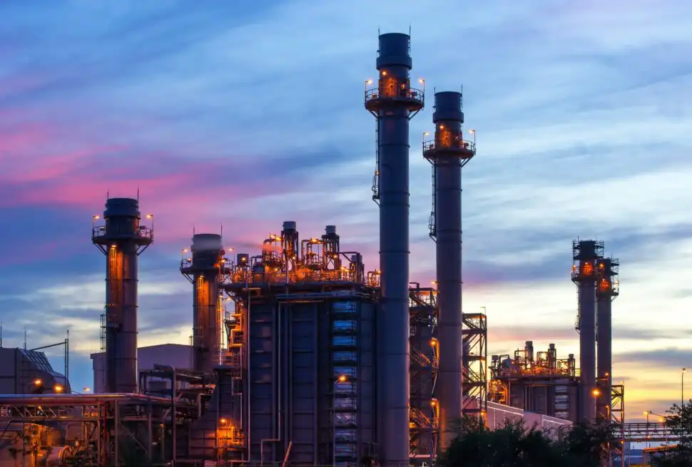 Industrial plant with tall chimneys against a colorful sunset sky