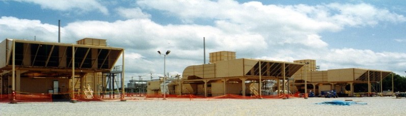 Industrial site with structures for dry emission reduction under a blue sky.
