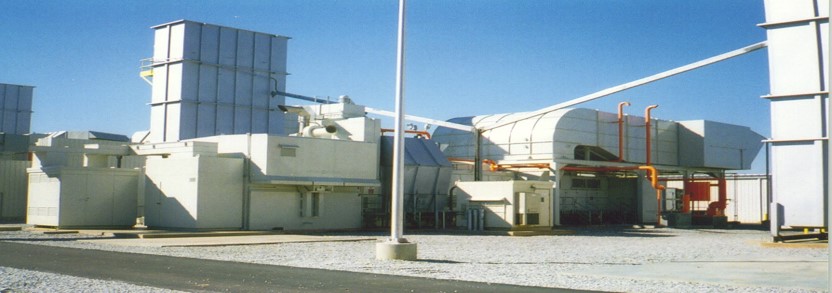 Industrial facility with large ducts and equipment under a clear blue sky.