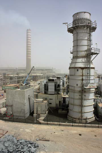 Industrial site featuring large chimneys and equipment under cloudy skies.