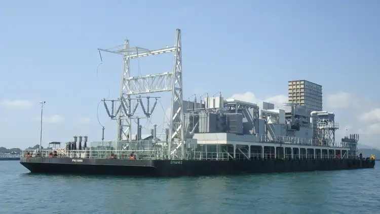 Floating power station on calm waters under a clear sky.