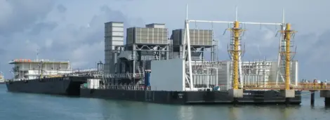 Gas turbine reapplication platform docked at a port, showcasing industrial energy equipment.