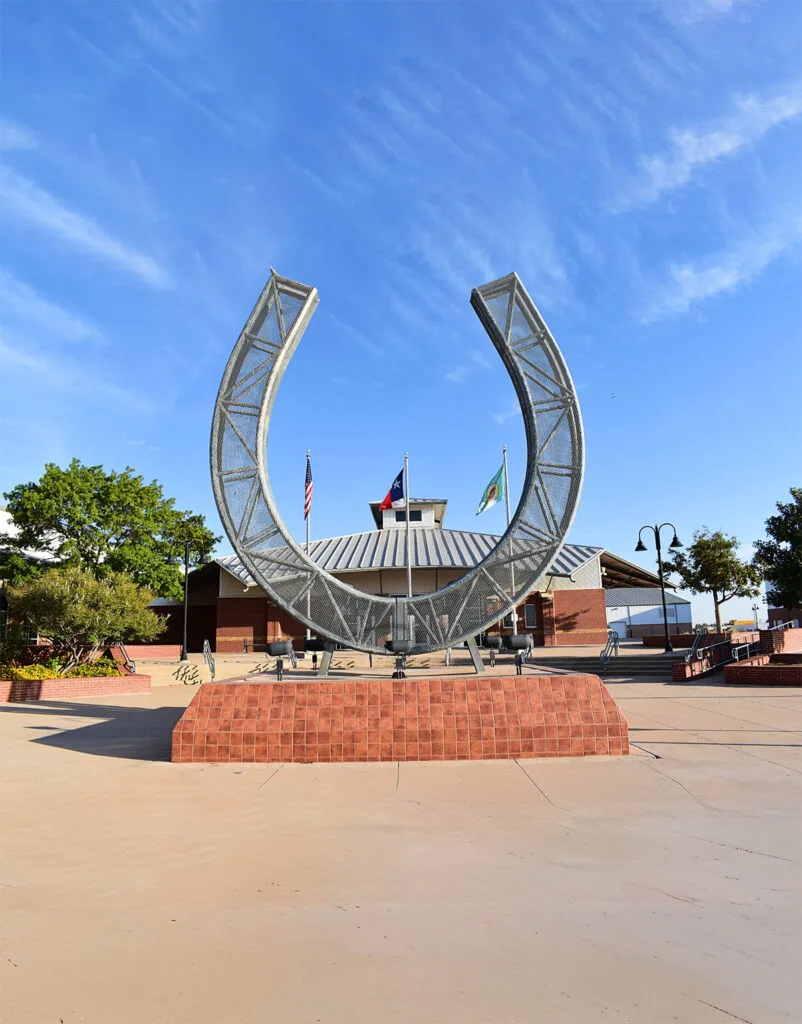 Metal horseshoe sculpture on brick pedestal outdoors