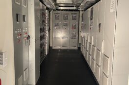 Industrial electrical room with control panels and ducts.
